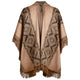 A woven poncho with geometric diamond patterns hangs against a plain white background. It features brown fringes along the edges and a warm, earthy color palette.