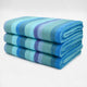 Pululahua baby alpaca wool blanket – three folded wool blankets, featuring horizontal blue, teal, and purple stripes, stacked neatly against a plain, light gray background