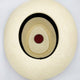 A cream-colored hat viewed from above, displaying a circular black band inside, with a red sticker at the bottom of the interior, set against a plain white background.