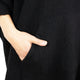 A hand is inserted into a pocket of a black woolen garment, showcasing the texture of the fabric and the natural coloration of the skin against it.