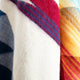 A close-up of three intertwined woolen fabrics displaying plaid patterns in blue, red, and orange hues, creating a vibrant and textured composition.