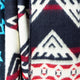 A woolen fabric displays geometric patterns in red, black, and white, with triangular and star shapes. Its folded texture is visible against a contrasting blue section on the left.