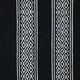Black fabric features vertical white geometric patterns with diamond shapes, arranged in stripes. The design creates a symmetrical, intricate look against the plain dark background.