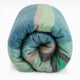 Sucua baby alpaca wool blanket – a rolled-up, multicolored wool blanket featuring blue, green, and pink stripes rests on a plain white background