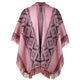 A pink shawl featuring a geometric pattern with black diamond shapes, drapes open with fringed edges, set against a plain white background.