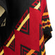 A fabric displays a vibrant geometric pattern featuring red, yellow, and black triangular and angular shapes. The colors create a striking contrast, suggesting a dynamic, eye-catching design.