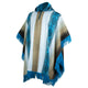 A poncho with teal, beige, and off-white vertical stripes features intricate patterns and fringed edges, displayed on a stand against a white background.