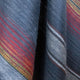 Huasaga baby alpaca wool blanket – woolen fabric drapes gently, displaying diagonal stripes in blue, red, yellow, and white tones. The textured surface creates a warm and intricate visual appeal