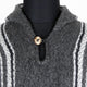 Cozy gray sweater, buttoned at the neck, featuring white and dark striped patterns, displayed on a black mannequin torso.