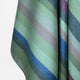Imbabura baby alpaca wool blanket – a soft, striped fabric hangs gently, featuring horizontal bands of pastel greens, blues, pinks, and grays, against a plain white background