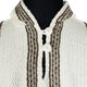 A cream wool sweater features two buttons near the collar, with brown and dark brown vertical stripes. It's displayed on a black mannequin, focusing on the upper chest area.