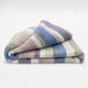 Yunga baby alpaca wool blanket – a folded blanket displays pastel stripes of green, pink, blue, and purple on a white background. It lies neatly against a plain, light backdrop