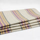 Quijos alpaca wool blanket – a folded blanket featuring purple, yellow, and gray horizontal stripes rests on a plain white surface, creating a cozy, orderly appearance