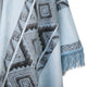 A light blue fabric, featuring geometric black and grey patterns, drapes softly. The edge of the fabric is adorned with light blue fringe, creating a textured appearance.