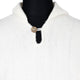 A knitted white garment with a high collar features a single decorative brown button near the neckline, displayed on a black mannequin torso.