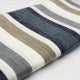 Pilishurco baby alpaca wool blanket – a folded, horizontally striped wool blanket lies on a white surface, featuring alternating bands of grey, white, beige, and dark blue, creating a cozy and inviting appearance