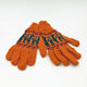 Orange knitted gloves lie flat, featuring dark green and maroon patterns near the wrists, set against a plain white background.