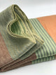 Latacunga alpaca wool throw blanket – a woven blanket is folded neatly, featuring horizontal stripes in muted green, orange, and brown tones. It rests on a plain, light-colored background