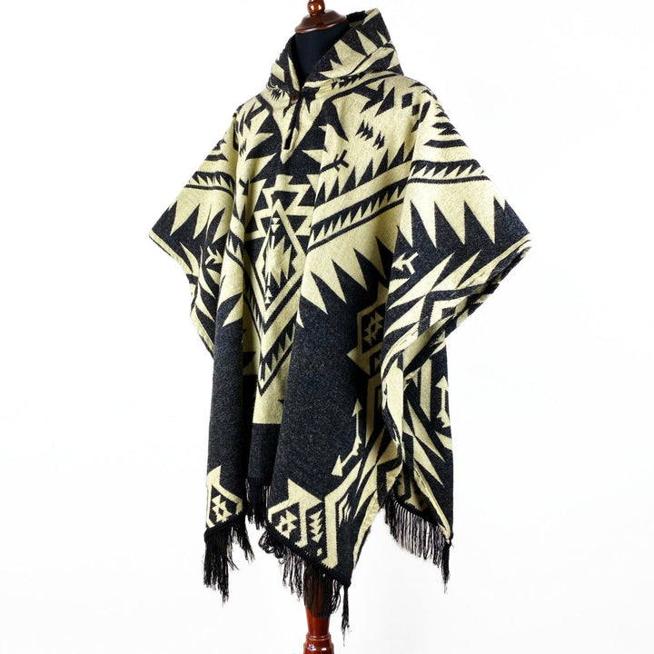 Tarqui alpaca wool hooded poncho – a poncho with a geometric pattern, draped over a mannequin. The design features beige and black tones, with fringe at the hem. The background is plain white