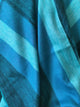 Cajabamba alpaca wool blanket – blue fabric with broad horizontal stripes in varying shades, draped and folded, creating soft shadows and texture. The setting is an abstract close-up, focusing on the pattern