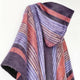 A multicolored striped scarf hangs elegantly, showcasing shades of purple, rust, and black; the soft fabric suggests warmth against a plain, light background.