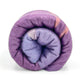Chuquipata baby alpaca wool blanket – a rolled-up purple blanket is tightly coiled, showcasing its soft texture and subtle pastel hues, set against a plain white background
