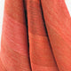 Cusubamba baby alpaca wool blanket – red fabric drapes softly, showcasing its texture and subtle variations in hue. The close-up view highlights its woven and fuzzy qualities against a plain background