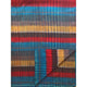Alpaca wool queen blanket – a colorful blanket displays horizontal stripes in red, blue, yellow, and brown hues, with a corner folded back, showcasing the pattern's reverse side in a plain setting