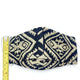 A fabric face mask featuring a black and beige geometric pattern lies on a white surface. A yellow measuring tape beside it shows a length of approximately 3 inches.