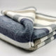 Pilishurco baby alpaca wool blanket – a folded blanket displaying thick horizontal stripes in shades of gray, white, and tan, resting on a smooth, neutral background