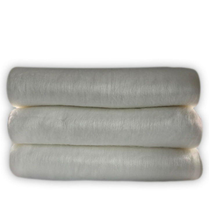 Miazi baby alpaca wool blanket – three thick, white rolls of cotton are stacked horizontally, showcasing their fluffy texture, set against a plain white background