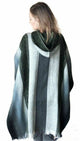 A person stands wearing a hooded poncho with vertical stripes in shades of grey and black. The background is white, emphasizing the garment's texture and pattern.