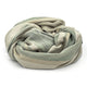 Deleg baby alpaca wool blanket – a soft, beige and green blanket forms a loose coil, with gentle folds and shadows, resting on a plain white background