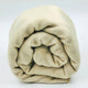 Quisapincha baby alpaca wool blanket – a beige, fleece blanket is rolled tightly, resting against a plain, light gray background