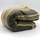 Chalua baby alpaca wool blanket – a rolled blanket features dark and light horizontal stripes, resting on a flat surface, with a light background