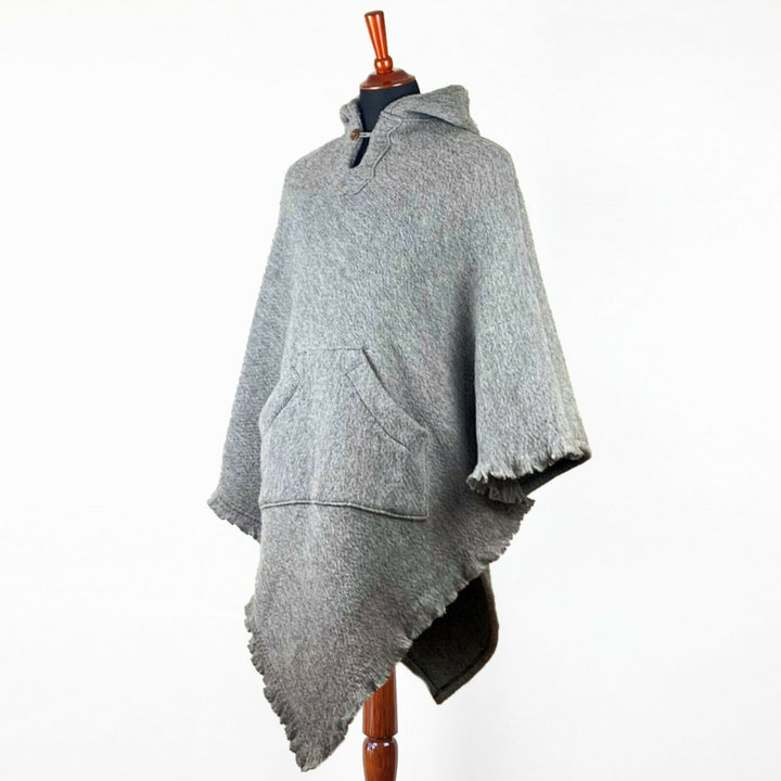 A gray poncho with a hood and a front pocket is displayed on a mannequin, set against a plain white background.