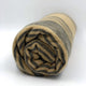 Chalua baby alpaca wool blanket – a rolled-up, striped woolen blanket rests on a plain white surface. The blanket's colors alternate between dark grey and beige