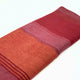 Pallatanga baby alpaca wool blanket – a folded, woolen blanket displays horizontal stripes in shades of red, orange, and purple against a plain white background