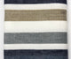 Pilishurco baby alpaca wool blanket – a knitted fabric displays horizontal stripes in alternating colors: dark gray, cream, olive green, and teal, arranged symmetrically. The background is plain white