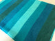 Cajabamba alpaca wool blanket – a folded fabric displays horizontal stripes in varying shades of blue and teal, lying on a flat light-colored surface