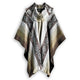 A woolen poncho with geometric patterns and a fringed collar hangs against a plain white background, displaying an earthy gradient from light to dark tones.
