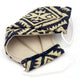 A cloth face mask, featuring a beige and black geometric pattern, rests open with white elastic straps visible, set against a plain white background.