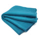 Moyaschucho baby alpaca wool blanket – a folded turquoise blanket rests on a surface, displaying its soft, plush texture. The blanket is neatly arranged with visible ends and smooth fabric layers