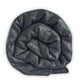 Suncamal baby alpaca wool blanket – a thick, dark grey knitted blanket is rolled tightly, creating a coiled appearance. The texture appears soft and warm, set against a plain white background