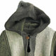 A thick, hooded grey and dark green woolen garment is displayed on a hanger. It features a wooden button closure at the collar and vertically stitched patterns.