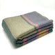 Guagua baby alpaca wool blanket – a folded, striped wool blanket with green, beige, and pink patterns lies neatly stacked on a plain white surface
