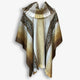 Poncho hanging vertically, features geometric patterns and earthy tones of brown, beige, and cream in a symmetrical design. It is draped against a plain, light background.