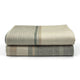 Deleg baby alpaca wool blanket – two neatly folded woolen blankets lie stacked, featuring subtle beige, green, and tan stripes, on a plain white surface, suggesting a clean, minimalist environment