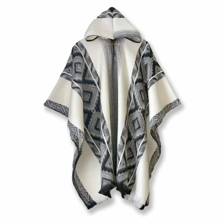 A hooded poncho features geometric patterns in black and gray on a white background, hanging against a plain white backdrop.