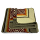 A folded wool blanket showcases intricate patterns in earth tones, featuring geometric designs and gradient stripes, resting on a white background for display.